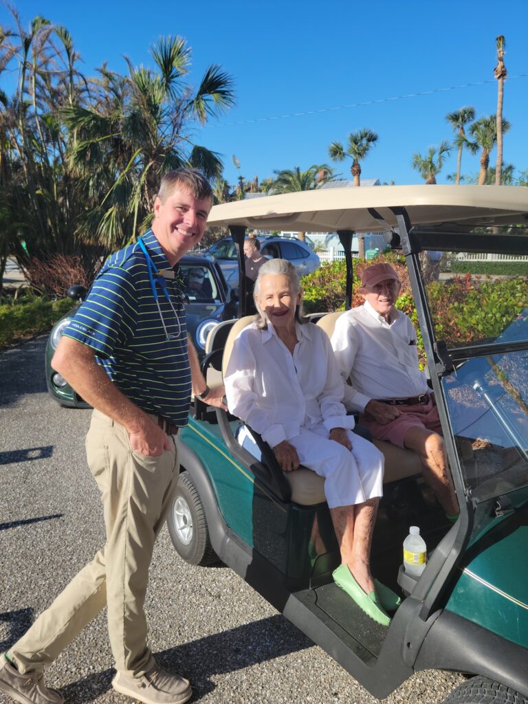 older couple in golf cart next to doctor