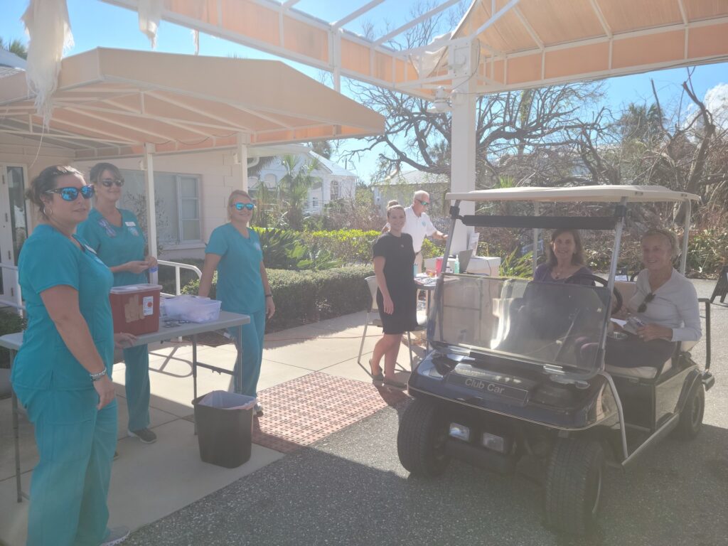 golf cart driving through vaccine drive-through, showing three nurses