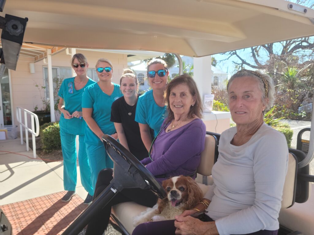 nurses posing next to golf cart with two women and dog