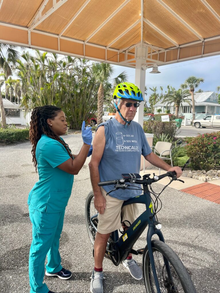 nurse getting ready to vaccinate a man on a bicycle at a vaccine drive-through