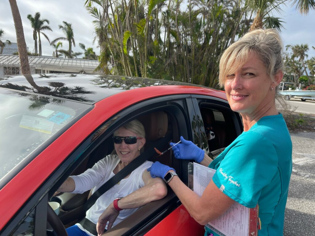 nurse getting ready to vaccinate a woman in her car at a vaccine drive-through